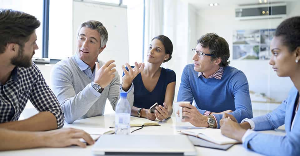 Photo of employees listening to their manager at a table