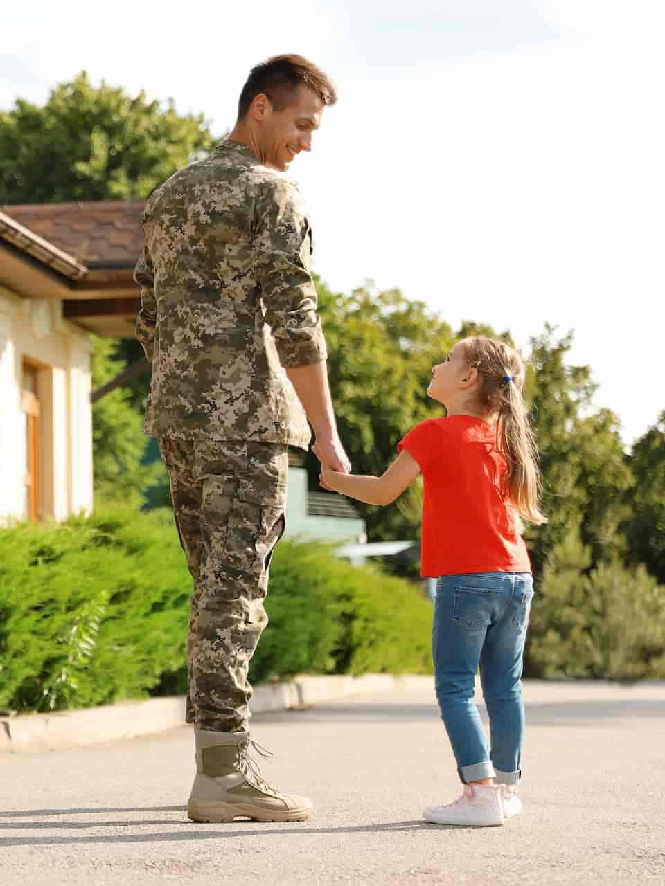 veteran father wears service uniform while walking with child up driveway to their home